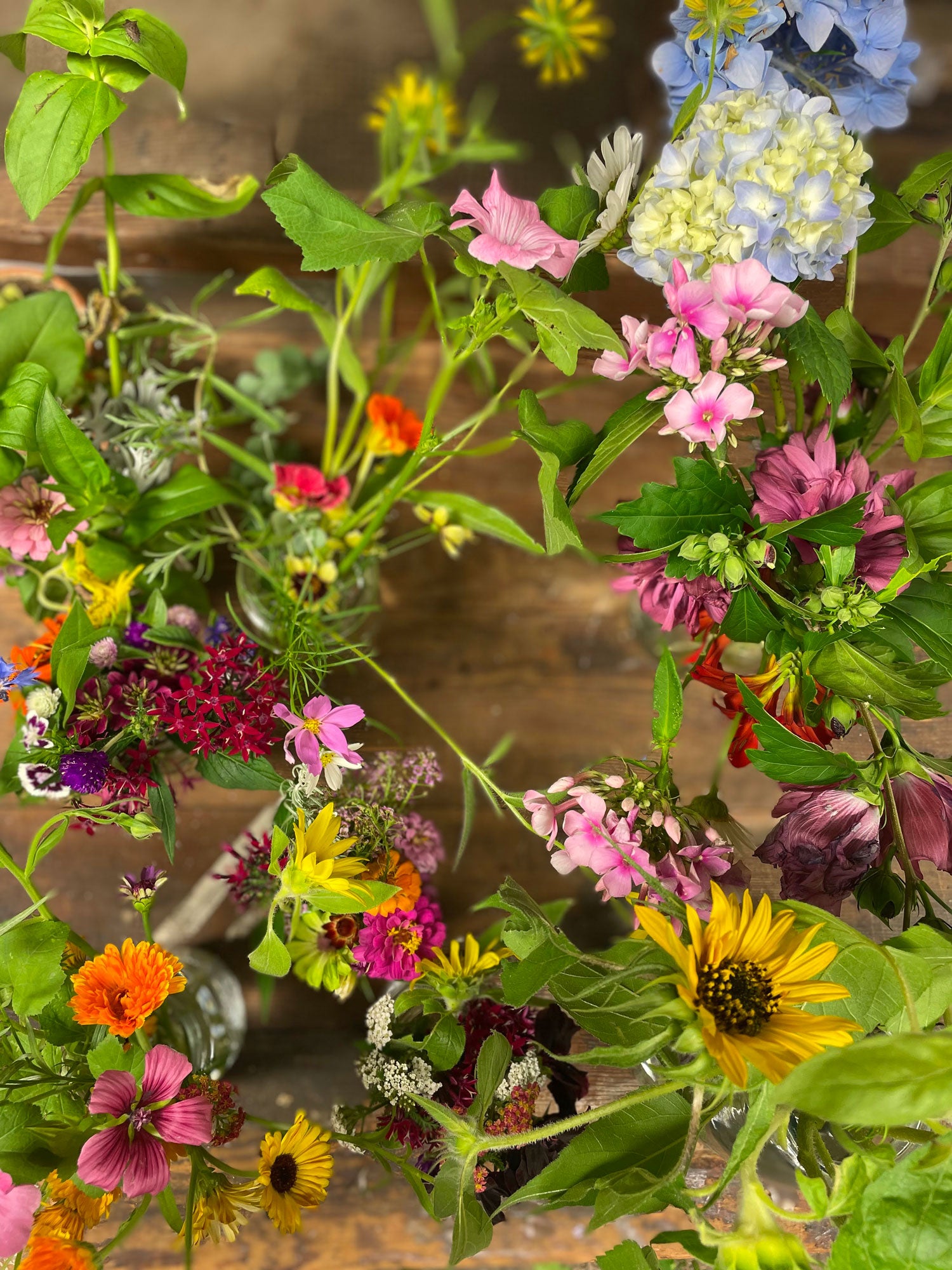 Colorful flowers and green leaves on a wooden surface.