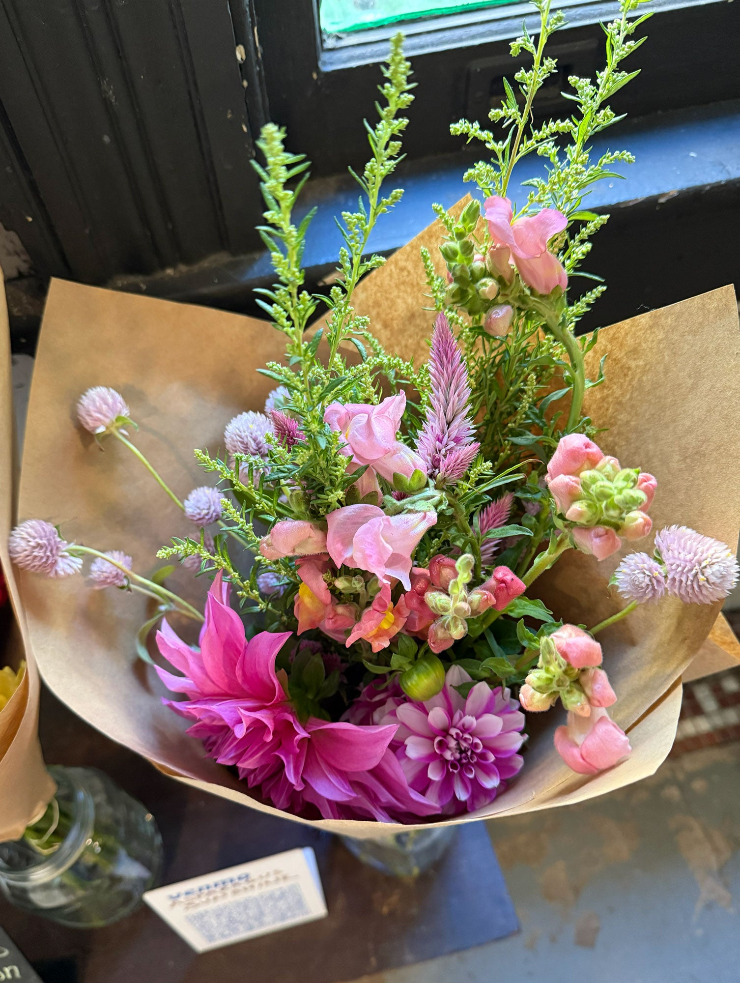 Bouquet of flowers wrapped in brown paper on a table.