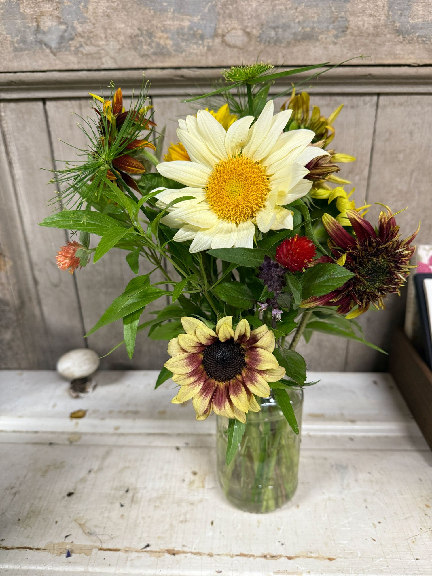 Bouquet of flowers in a clear vase on a wooden surface with a rustic background.