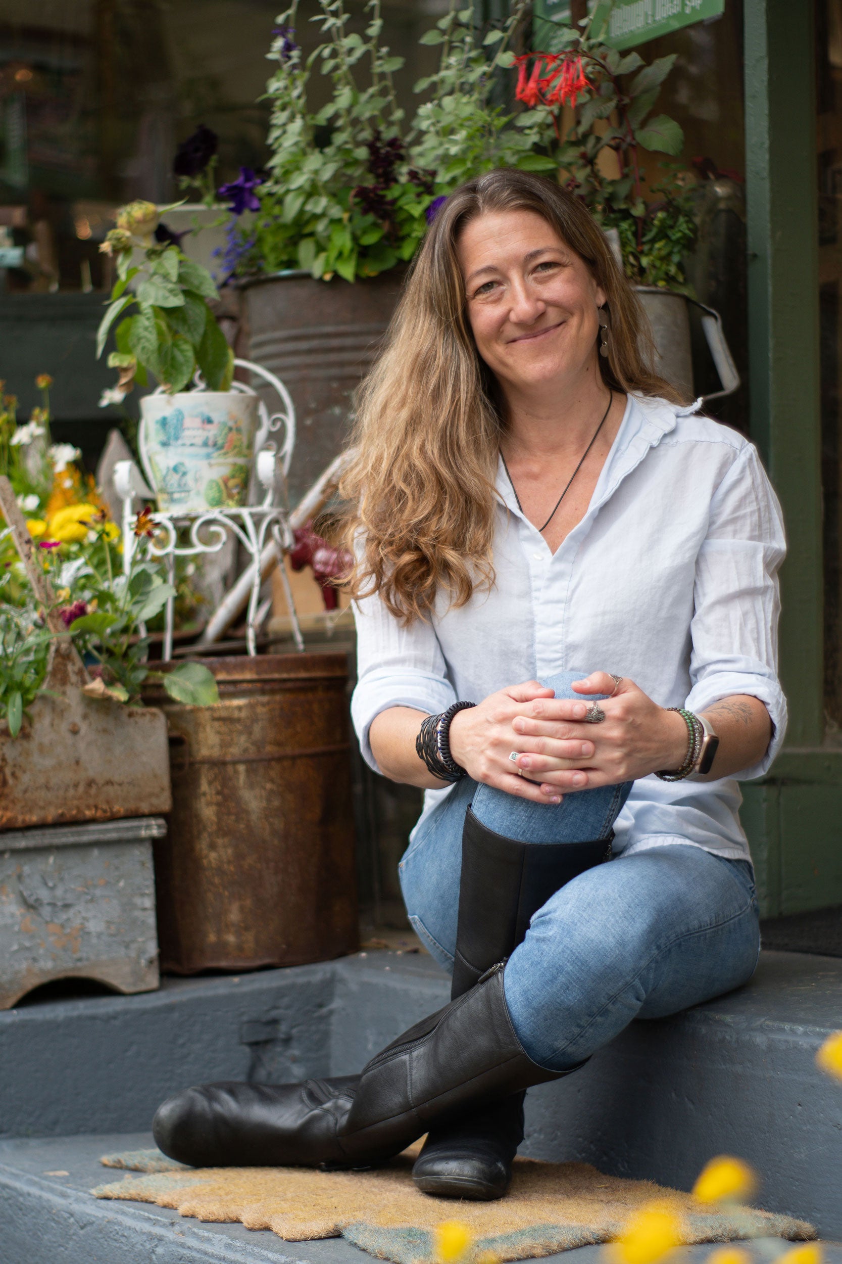 Lauren Chamberlain owner of Asparagus Sunshine sitting among plants and flowers in a garden setting