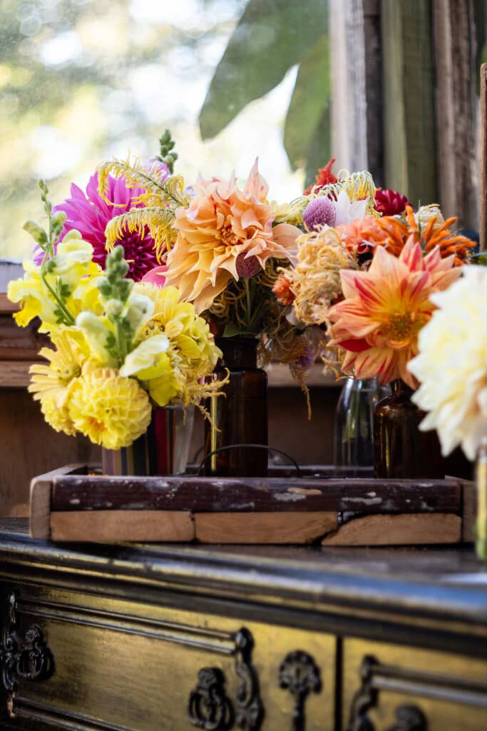 Colorful floral arrangements on a wooden surface with a blurred natural background