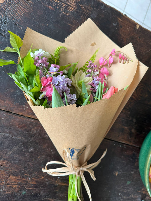 Bouquet of flowers wrapped in brown paper on a wooden surface